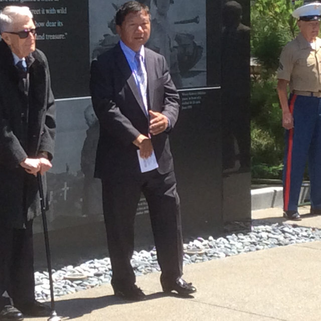 photo of Man J. Kim in front of the wall, speaking